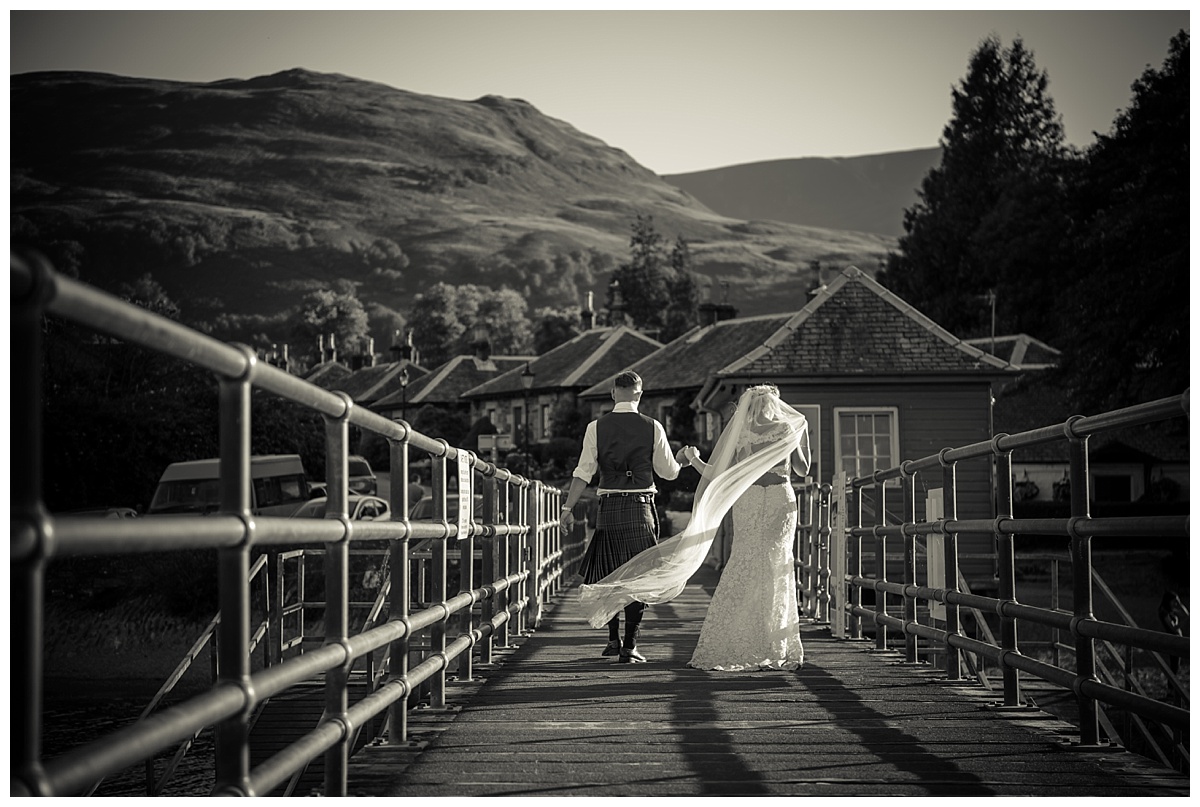 bride and groom walking on luss pier loch lomond